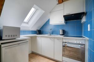 a small kitchen with white cabinets and blue tiles at Eagle Suite Charmante Dachgeschosswohnung mit Design & Ausblick in Zurich +4 photos