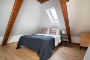 a bedroom with a bed with a blue blanket and a window at Eagle Suite Charmante Dachgeschosswohnung mit Design & Ausblick in Zurich