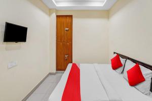 a bedroom with a bed with red pillows and a television at Hotel O Mt Stays in Noida