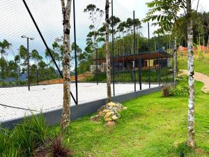 a fence with palm trees in front of a house at Cabana Panorama - Parque Floresta Alta in Rodeio