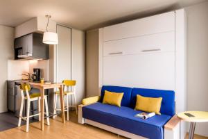 a living room with a blue couch and a table at Aparthotel Adagio access Colombes La Défense in Colombes