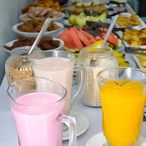 a table with three glasses of milk and a plate of food at Hotel Ipê in São Luiz Gonzaga