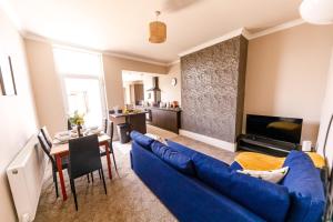 a living room with a blue couch and a table at Spacious 4Bed Parking & Wi-Fi - Contractor Stays in Pallion