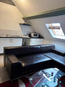 ein Wohnzimmer mit einer schwarzen Ledercouch in der Küche in der Unterkunft Marie home in Brüssel