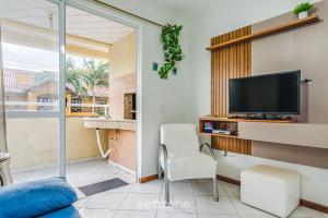 ボンバスにあるApto 2Q c varanda a 220m da praia de Bombas FDL103のリビングルーム(テレビ、白い椅子付)
