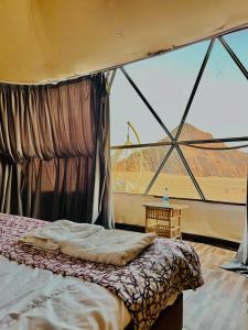 a bed in a tent with a large window at Rum New Luxury Camp in Wadi Rum