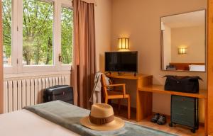 a bedroom with a bed with a desk and a television at Hotel Estel in Berga