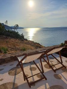 a bench sitting on the beach with a view of the ocean at Ithaca in Perdika