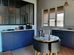 a kitchen with blue cabinets and a small table at L'Ecrin Dakoté in Sassenay