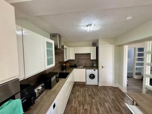 a kitchen with white cabinets and a washer and dryer at Superb Homestay in Cowlairs
