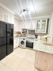 a kitchen with white cabinets and a washer and dryer at Fully Furnished 3 bedroom apartment rental in Roodepoort