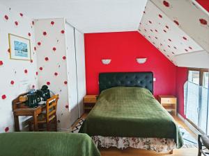 a bedroom with a red wall with a bed and a desk at Chambres Les Salles in Beauvoir