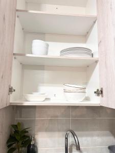 a kitchen shelf with plates and bowls on it at Fully Furnished 3 bedroom apartment rental in Roodepoort