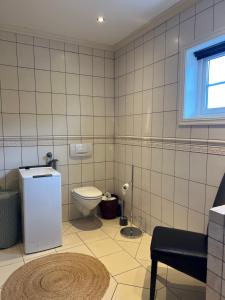 a tiled bathroom with a toilet and a window at Huset ved fergekaien på Moskenes in Moskenes +26 photos
