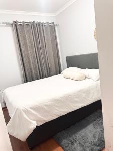 a bedroom with a bed with white sheets and a window at Fully Furnished 3 bedroom apartment rental in Roodepoort +11 photos