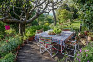 a table and chairs on a wooden deck in a garden at Casa in Bioedilizia con Bio Piscina Naturale – Ai Due Gelsi in Grancona