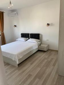 a bedroom with a bed with white sheets and wooden floors at Vila Antonia in Năvodari +2 photos