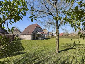 a house in a field with a tree in the foreground at Farmhouse in Limburg with Private Sauna in Roggel