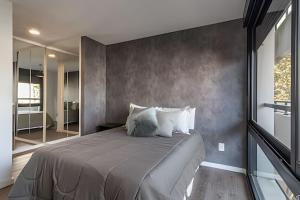 a bedroom with a large bed with a concrete wall at Live Soho in Montevideo