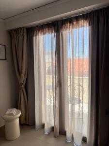 a bathroom with a window with curtains and a toilet at Agali Studios in Mytilene +70 photos