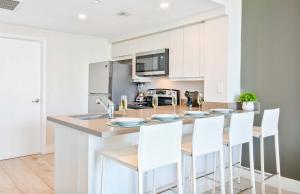 a kitchen with white cabinets and a counter with white chairs at MVR - The Best of Work Relaxation in One in Miami