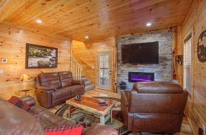 a living room with leather furniture and a flat screen tv at Pebblestone Lodge in Pigeon Forge