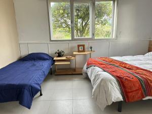a bedroom with two beds and a desk and two windows at Casa Sanuk in Poio