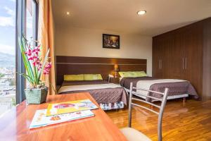 a hotel room with two beds and a table at Hotel Portugal Confort in Ambato