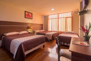 a hotel room with two beds and a table at Hotel Portugal Confort in Ambato
