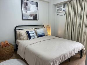 um quarto com uma cama com lençóis brancos e uma janela em Verdon Parc Davao City with Balcony by darpm em Dávao
