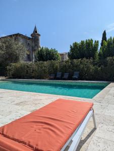a swimming pool with a red mattress next to a house at Domaine de Pélican in Gignac