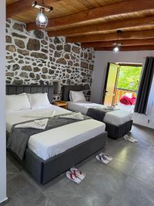 two beds in a room with a stone wall at Guesthouse Te Tata in Theth +27 photos