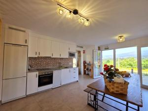 a kitchen with white cabinets and a table with flowers on it at Casa Rural Abreu Do Louro in Arbo