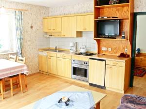 une petite cuisine avec des placards en bois et une télévision dans l'établissement Ferienwohnung Schwarzwaldsegen mit Balkon, à Todtmoos
