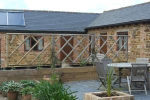 een patio met een tafel en stoelen voor een gebouw bij Handley Barn in Silverstone