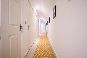 a hallway with a yellow tile floor and a white door at Two Bedroom Flat By Littlepiggyrentals Short Lets & Serviced Accommodation Cranfield With Balcony & Fast Wi-Fi in Cranfield