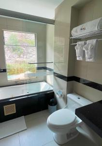 a bathroom with a white toilet and a bath tub at Villasol Hotel in Lunahuaná