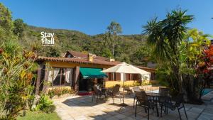 une terrasse avec des chaises et un parasol en face d'une maison dans l'établissement Mansão Bardô em Morin-5qts-Piscina e Academia-SH111D, à Petrópolis