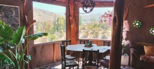 a table and chairs in a room with a large window at Alojamiento y Refugio Cósmico Torreon in Comunidad Campo de Ahumada +51 photos