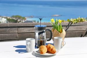 una mesa con cafetera, cruasanes y tazas de café en Villa Aqua by Totalstay en Ciudad del Cabo