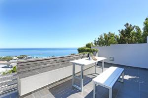 Biały stół i ławka na balkonie z widokiem na ocean w obiekcie Villa Aqua by Totalstay w Kapsztadzie