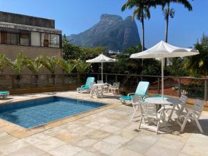 a pool with chairs and tables and an umbrella at Beach Front 2 Bed Rooms - Balcony with Full Sea View - Praia do Pepê in Rio de Janeiro