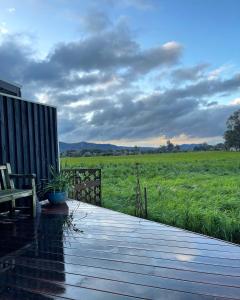 a wooden deck with a bench and a field of grass at Lume King Valley in Whitfield +22 photos