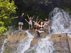 un gruppo di persone che si trovano sulle rocce di fronte a una cascata di Isabel hostal a Juayúa