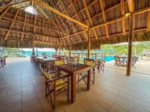 a restaurant with tables and chairs and a straw roof at Hotel Chiniu in Palomino