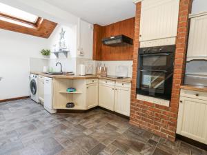 une cuisine avec des placards blancs et un mur en briques dans l'établissement Saddlers Cottage, à Weymouth