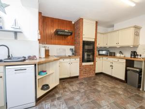 une cuisine avec des placards blancs et un mur en briques dans l'établissement Saddlers Cottage, à Weymouth 9 autres photos