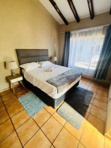 ein Schlafzimmer mit großem Bett und Fenster in der Unterkunft Exquisite cottage in Doringkloof in Centurion