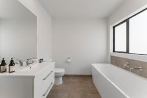 a white bathroom with a tub and a toilet at Holiday Hub - Taupo in Taupo +18 photos