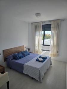 Un dormitorio con una cama y una ventana grande. en Piscina y Pádel al lado del Mar, en Torredembarra